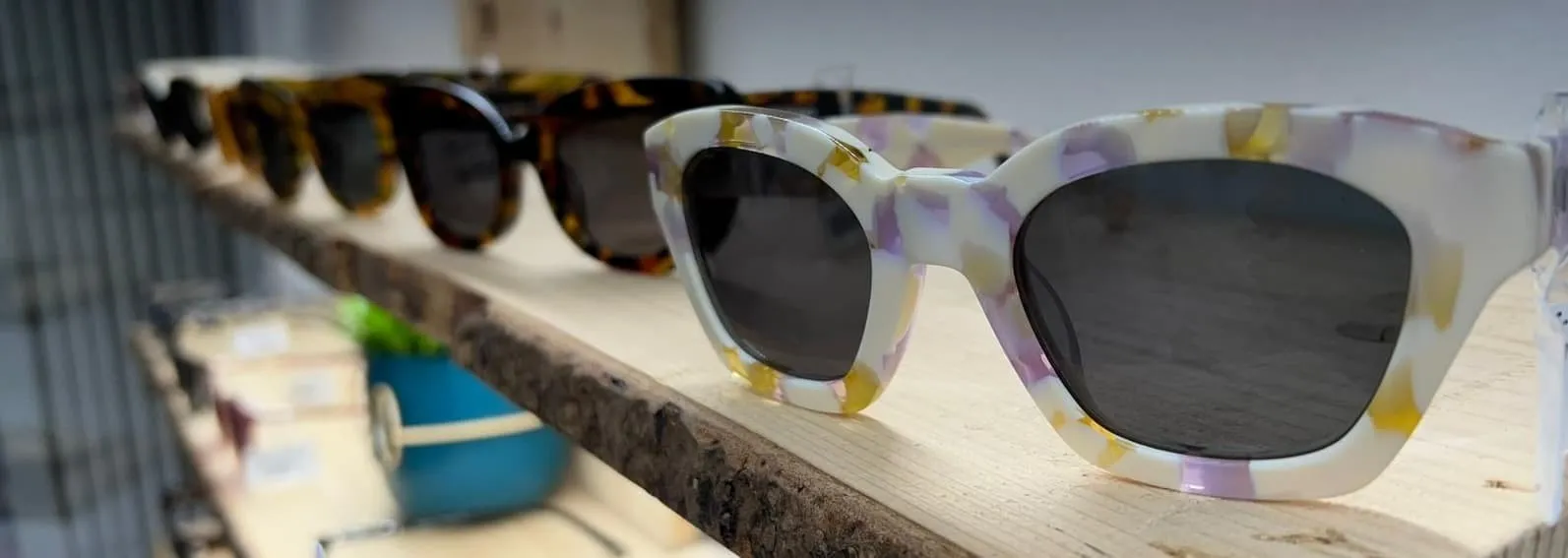 Gafas de sol de colores en un estante de madera del centro óptico Siente